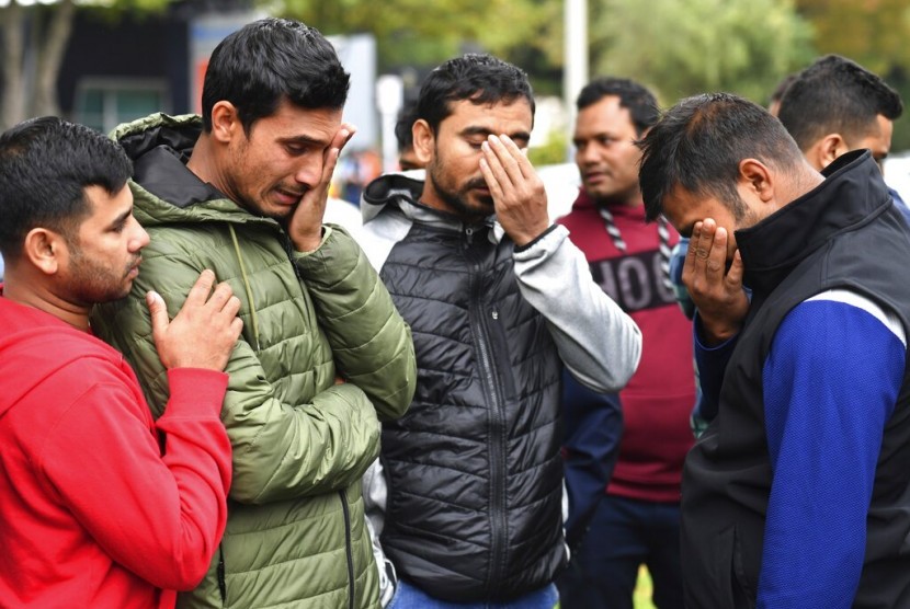 Teman para korban penembakan masjid di Christchurch, Selandia Baru berduka di luar sebuah pusat pengungsi, Ahad (17/3).