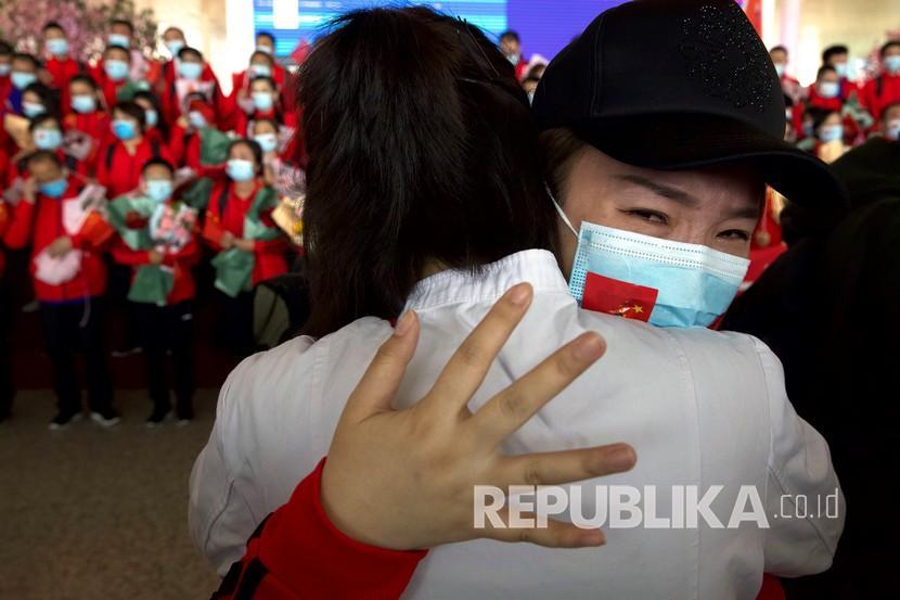 Tenaga medis dari Provinsi Jilin memeluk rekannya ketika bersiap untuk pulang di Bandara Internasional Tianhe Wuhan.