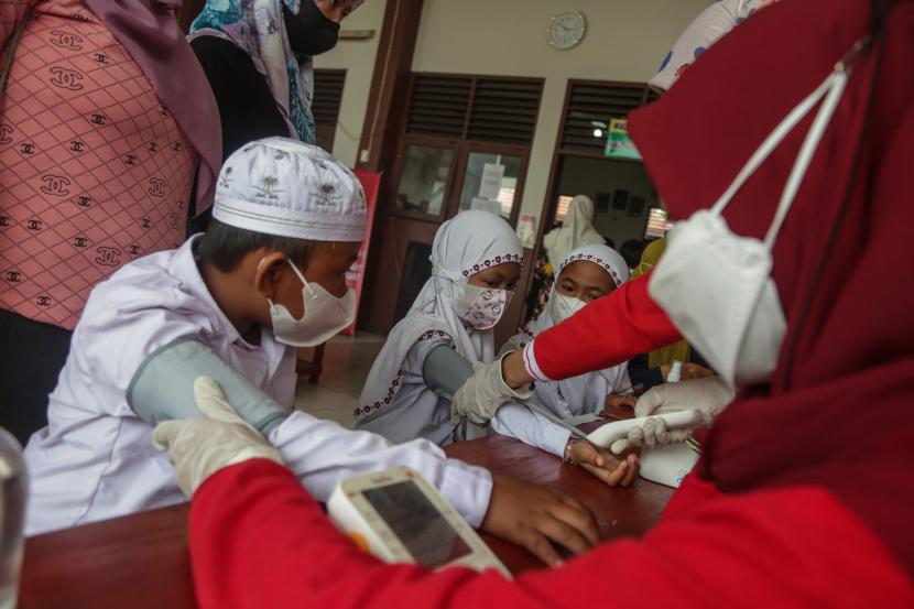 Tenaga medis memeriksa kesehatan siswa sebelum disuntik vaksin Sinovac saat giat vaksinasi COVID-19 massal bagi anak usia 6-11 tahun di SD Nurul Ihsan, Palangkaraya, Kalimantan Tengah, Senin (27/12/2021). Dinas kesehatan Kota Palangkaraya mencatat capaian vaksinasi secara umum di wilayah itu mencapai 102,27 persen atau 228,489 orang dosis pertama dan 83,63 persen atau 186,846 orang untuk dosis kedua dari keseluruhan total target sasaran 223.387 orang.