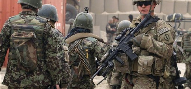 Tentara Afghanistan (kiri) berjalan melewati seorang tentara pasukan ISAF di Panjwai, Provinsi Kandahar, Afghanistan. 