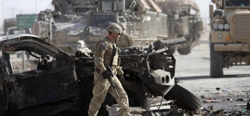 Tentara Amerika Serikat yang tergabung dalam Pasukan Bantuan Keamanan Internasional (ISAF) pimpinan NATO berjalan melewati bangkai kendaraan usai serangan bom di Kandahar, Kabul, Afghanistan, Kamis (19/1).