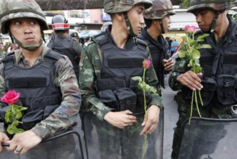 Tentara berjaga-jaga di Bangkok, sambil memegang bunga yang diselipkan pendukung mereka menyusul konflik berkepanjangan di Thailand.