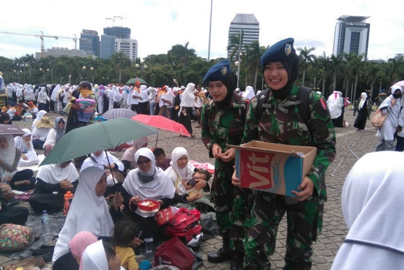 Tentara berjilbab bagikan air mineral kepada peserta Aksi Super Damai di Monas, Jumat (2/12).