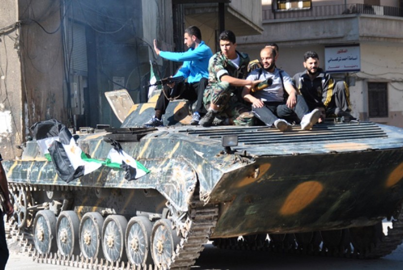 Tentara dan pemberontak Suriah berpose bersama di atas tank.