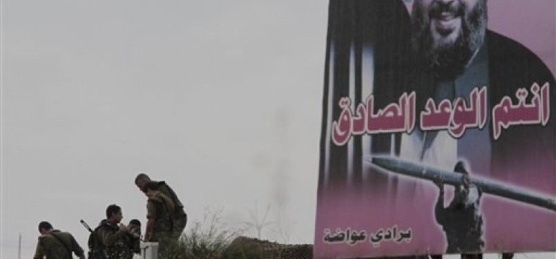 Tentara Israel berdiri di perbatasan Israel-Lebanon di mana poster pemimpin Hizbullah, Hassan Nasrallah, terpampang.