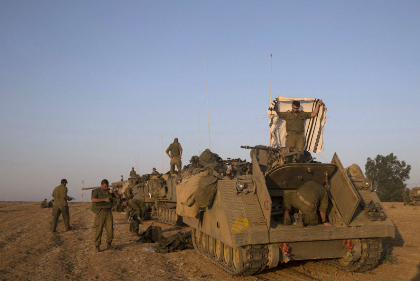 Tentara Israel terlihat dekat kendaraan lapis baja di luar jalur Gaja, Palestina, pada Kamis (10/7). 