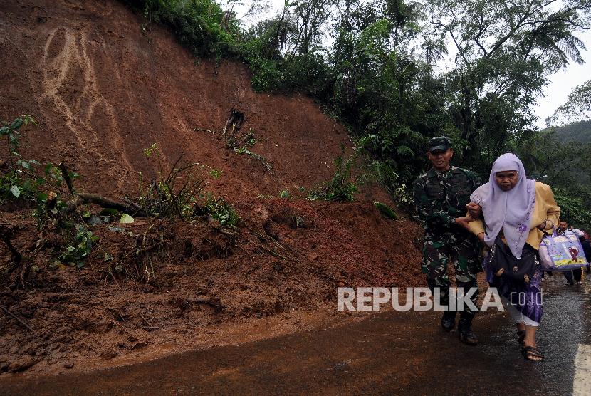 Tentara membantu salah satu warga berjalan saat evakuasi longsor di Jalur Utama Puncak, Bogor, Jawa Barat, Senin (5/2). 