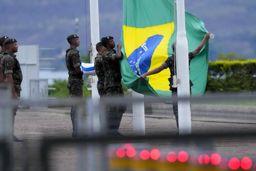 Tentara menurunkan bendera Brasil selama upacara di luar Istana Alvorada, kediaman resmi Brasil, setelah pemilihan umum ditutup di Brasilia, Brasil, Minggu, 2 Oktober 2022. Lebih dari 120 juta orang Brasil menggunakan hak pilihnya dalam pemilihan presiden pada Ahad (2/10/2022), pukul 08.00 pagi waktu setempat.