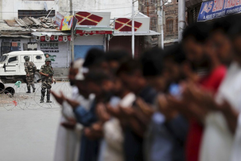 Tentara paramiliter India berjaga saat Muslim Kashmir menunaikan shalat Jumat di jalan di luar masjid setempat saat jam malam di Srinagar, India.