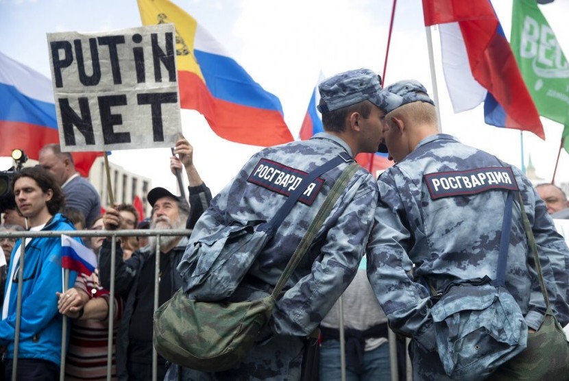 Tentara Rosguardia (Garda Nasional) berbicara saat demonstrasi meminta kandidat oposisi diikutkan dalam pemilihan parlemen September mendatang di Moskow, Rusia, Sabtu (20/7). Terlihat mereka membawa poster bertuliskan 'Putin No!'.