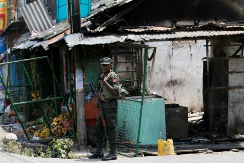 Tentara Sri Lanka berdiri di dekat toko yang dirusak di Kandy, Sri Lanka, 8 Maret 2018.