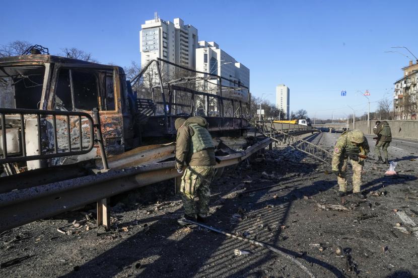 Tentara Ukraina menyelidiki puing-puing truk militer yang terbakar di sebuah jalan di Kyiv, Ukraina, Sabtu, 26 Februari 2022. Pasukan Rusia menyerbu ke arah ibu kota Ukraina Sabtu, dan pertempuran jalanan pecah saat pejabat kota mendesak penduduk untuk berlindung.