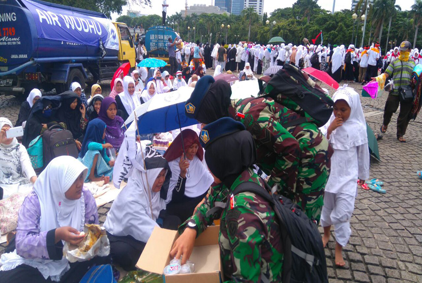 Tentara wanita berjilbab membagikan air mineral di aksi bela islam III di kawasan Monas, Jakarta, Jumat (2/12).