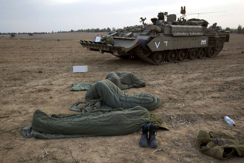  Tentara Zionis Israel tidur dalam kantong di samping tank dekat perbatasan dengan Jalur Gaza, Sabtu (17/11). (Reuters/Ronen Zvulun)