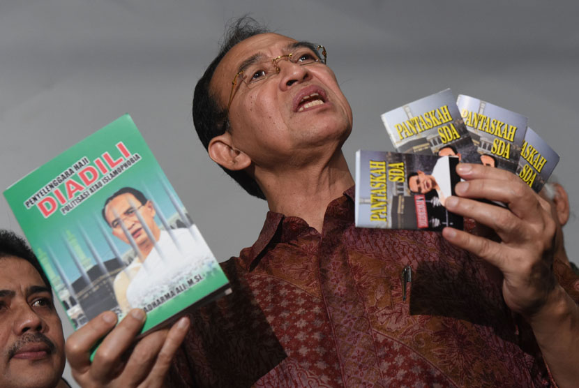 Terdakwa kasus dugaan korupsi dana haji Suryadharma Ali menunjukkan buku karyanya sebelum menjalani persidangan di Pengadilan Tipikor, Jakarta, Senin (11/1).