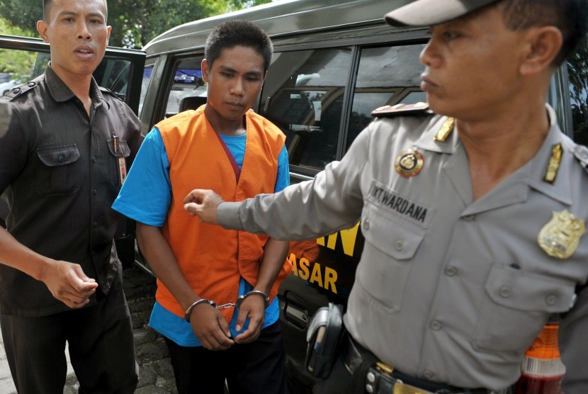 Terdakwa kasus pembunuhan anak, Agustay Hambamay (tengah), digiring petugas kejaksaan dan polisi saat akan menjalani persidangan di Pengadilan Negeri Denpasar, Bali, Kamis (17/12). 