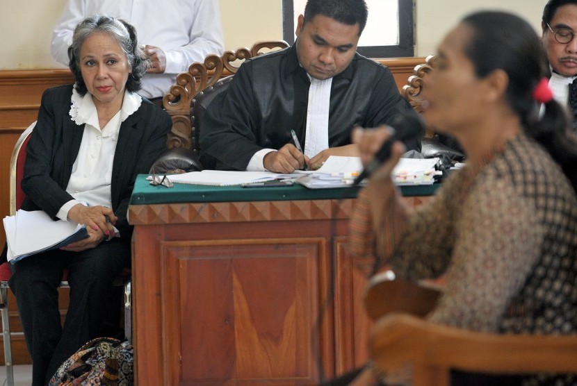 Terdakwa kasus pembunuhan anak, Margriet Megawe (kiri), mendengar keterangan saksi dalam persidangan di Pengadilan Negeri Denpasar, Bali, Kamis (17/12). 
