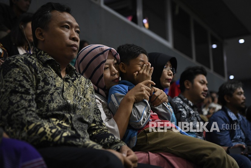 Terpidana kasus pelanggaran Undang-Undang Transaksi dan Informasi Elektronik (UU ITE), Baiq Nuril Maknun (tengah) memeluk anaknya disela-sela pembacaan pertimbangan amnesti untuk dirinya pada rapat paripurna DPR di Kompleks Parlemen Senayan, Jakarta, Kamis (25/7/2019).