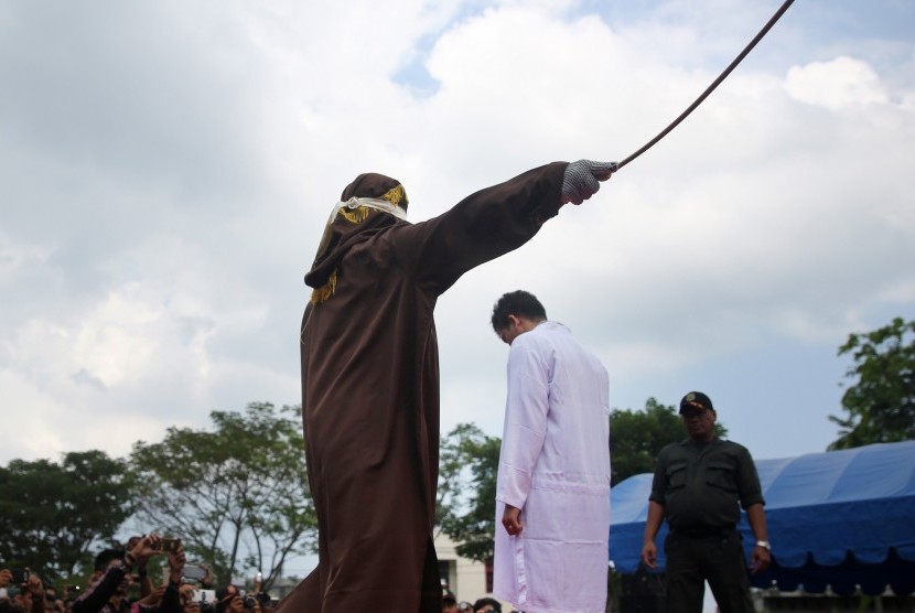 Terpidana pelanggar peraturan daerah (qanun) Syariat Islam (tengah) menjalani hukuman cambuk di halaman Masjid Rukoh, Kecamatan Syiah Kuala, Banda Aceh, Aceh.
