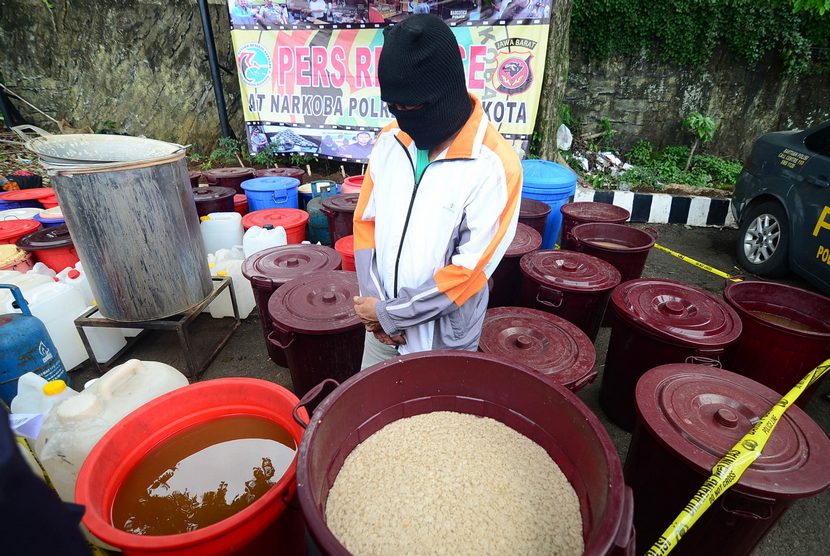   Tersangka Djun Min Sudiono (63) memperagakan proses pembuatan mininuman keras (miras) oplosan saat gelar perkara di Mapolres Bogor Kota, Jabar, Ahad (7/12). (Antara/Jafkhairi)