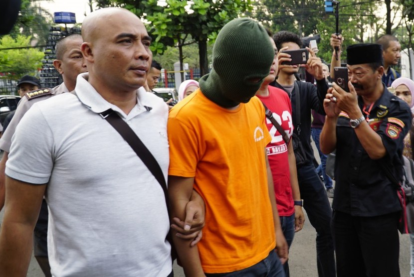 Tersangka dugaan penyebaran ujaran kebencian terhadap Iriana Joko Widodo berinisial DI dibawa petugas di Mapolrestabes Bandung, Jawa Barat, Selasa (12/9).