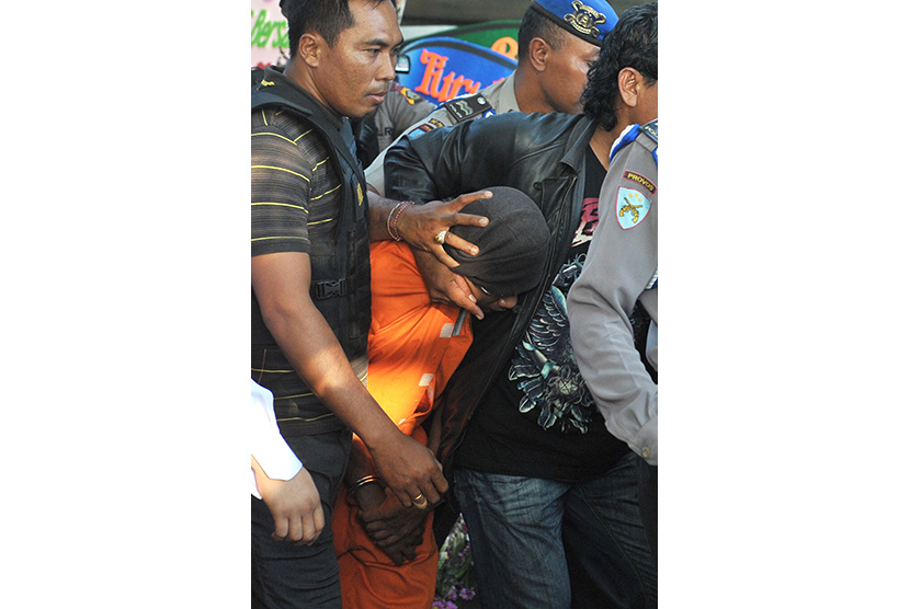   Tersangka kasus pembunuhan Angeline, Agus (tengah) digiring polisi saat mengikuti rekonstruksi di rumah majikannya, Margriet Megawe di Denpasar, Senin (6/7).  (Antara/Nyoman Budhiana)