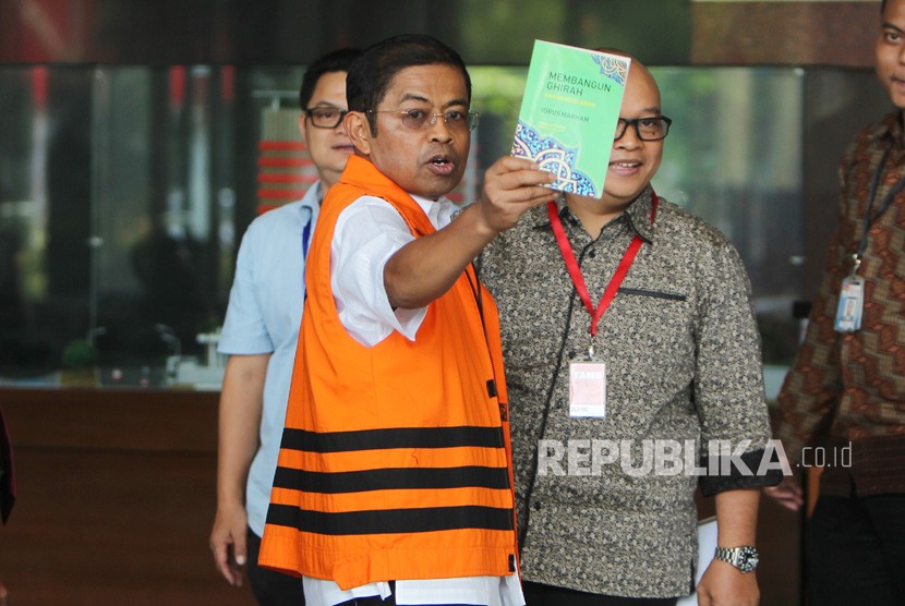 Tersangka kasus suap kesepakatan kontrak kerja sama pembangunan PLTU Riau-1 Idrus Marham menujukkan karya buku barunya yang berjudul Membangun Ghirah saat akan menjalani pemeriksaan di gedung KPK, Jakarta, Jumat (16/11/2018).