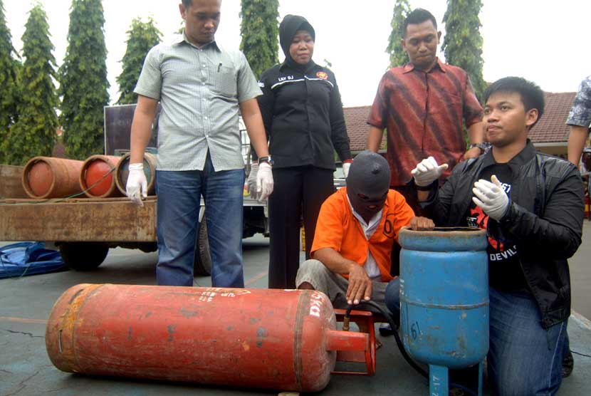 Tersangka pengoplos elpiji ilegal (kedua kiri) mempraktikan cara pengoplosan ketika ungkap kasus di Mapolres Pelabuhan Tanjung Perak Surabaya, Jatim, Jumat (10/1). 