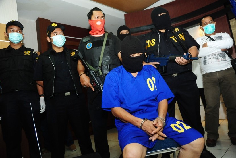 Tersangka penyelundup narkoba dari Malaysia, Win alias ER (tengah) dijaga ketat oleh sejumlah petugas Badan Narkotika Nasional (BNN) Kalbar, saat rilis ungkap kasus penyelundupan narkotika di Kantor Wilayah Bea dan Cukai Kalbar, di Pontianak, Rabu (8/7). 
