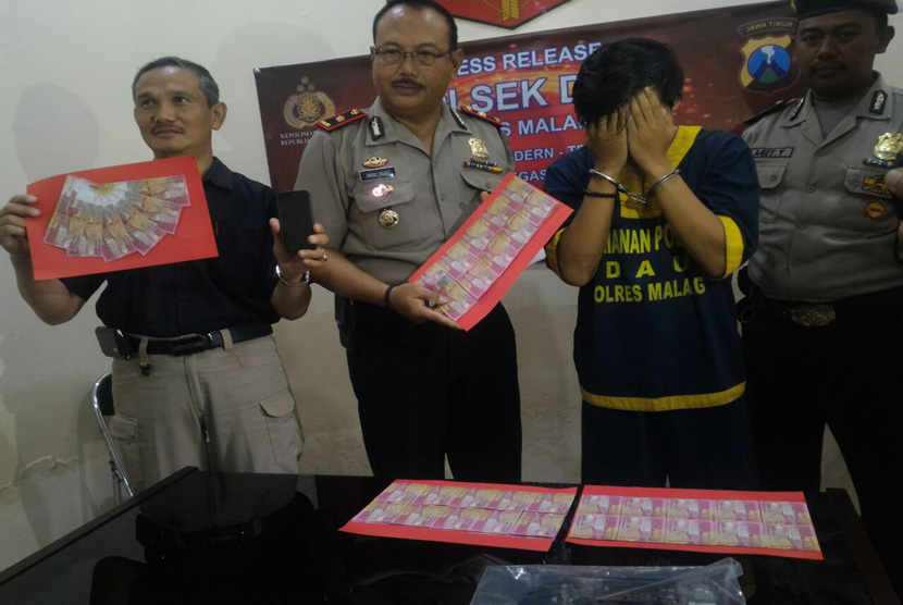 Tersangka Revangga dan barang bukti lembaran-lembaran uang palsu saat berada di Polsek Dau Kabupaten Malang, Selasa (24/1).