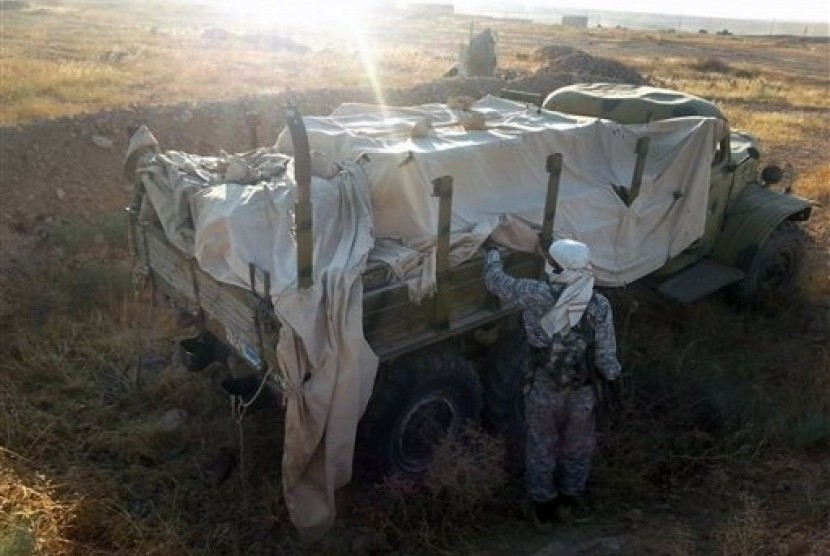 This image posted by the Raqqa Media Center, a Syrian opposition group, shows a fighter from the Islamic State group inspecting a military truck in Raqqa, Syria, Thursday, Aug. 7, 2014. 