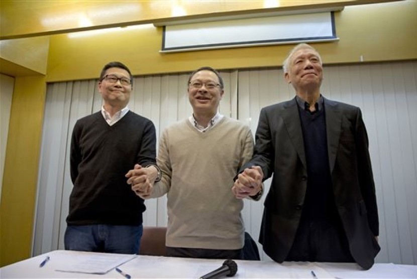 Three protest leaders, from left, Chan Kin-man, Benny Tai Yiu-ting and Chu Yiu-ming, pose for photographers during a news conference in Hong Kong Tuesday, Dec. 2, 2014 as they announce that they will surrender to police.