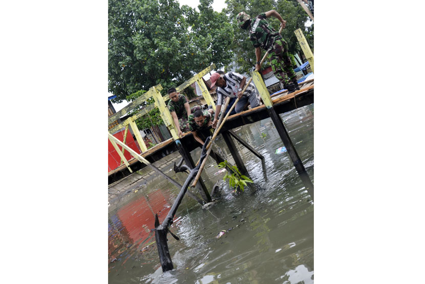 Tiga anggota Armed TNI AD bersama warga berusaha mengangkat ranting kayu dan sampah dari kanal di Kecamatan Maccini Sombala, Makassar, Sulawesi Selatan, Minggu (22/3). 