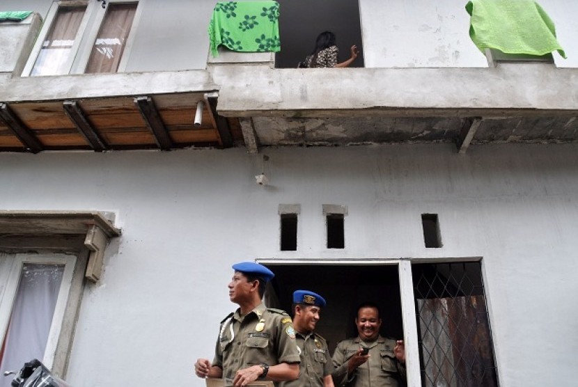 Tiga anggota Satuan Polisi Pamong Praja (Satpol PP) berdiri di depan pintu rumah kos usai gelar razia.