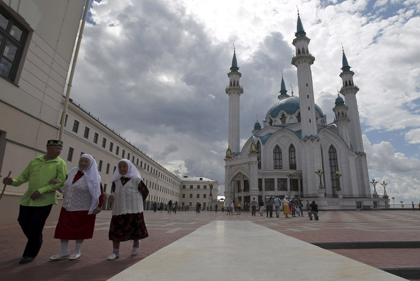 Tiga orang berjalan di sebuah lapangan dekat Masjid Kul Sharif di Kazan, ibukota Tatarstan Rusia. (Roman Kruchinin/Reuters)