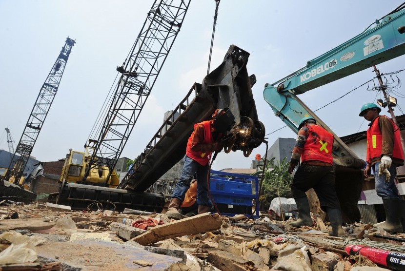 Tiga pekerja menyiapkan tiang pancang yang digunakan untuk pemasangan turap bantaran Sungai Ciliwung di Kampung Pulo, Jakarta, Selasa (25/8). 