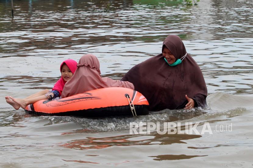 Tiga warga melintasi jalan Lintas Melawi yang terendam banjir di Kabupaten Sintang, Kalimantan Barat, Selasa (16/11/2021). Hingga kini kawasan Lintas Melawi yang merupakan pusat perdagangan Kota Sintang dan jalur utama menuju Kabupaten Kapuas Hulu tersebut masih terendam banjir. 