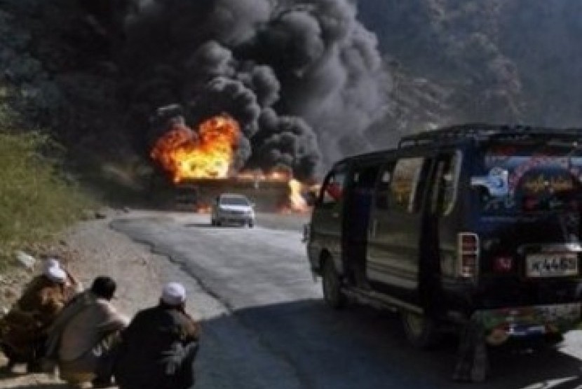 Tiga warga Pakistan, dari kejauhan melihat truk-truk NATO yang meledak
