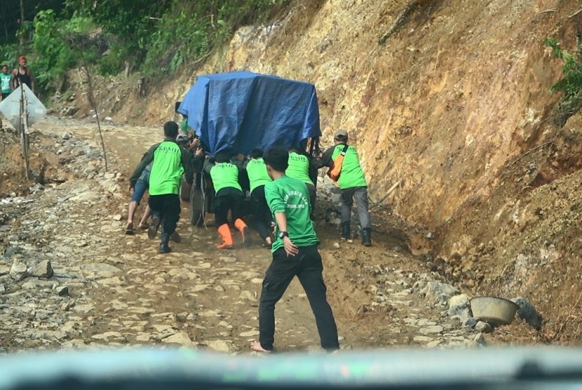 Tim BMH mendorong mobil yang membawa bantuan untuk warga korban banjir di Banten.