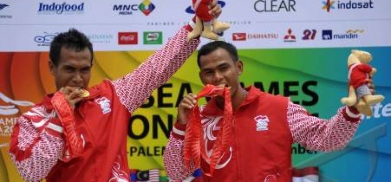 Tim dayung Indonesia,Anwar Tarra (kiri) dan Eka Octarorianus (kanan) mengigit medali emas usai penyerahan medali pada nomor final Kano 200 meter C2 putra SEA Games XXVI di arena dayung Situ Cipule, Karawang, Jawa Barat, Minggu (13/11).