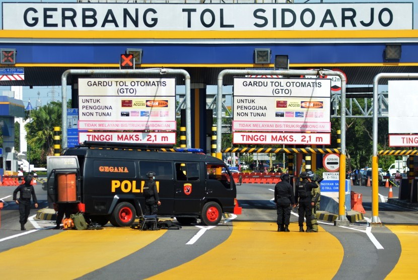 Tim Gegana Sat Brimob Polda Jawa Timur bersiap menjinakkan sebuah benda yang diduga bom di loket Pintu masuk Tol Sidoarjo, Jawa Timur, Jumat (18/5). Benda diduga bom berupa pipa yang dirangkai menjadi satu dengan kabel tersebut berhasil diledakkan oleh tim Gegana Sat Brimob Polda Jawa Timur.