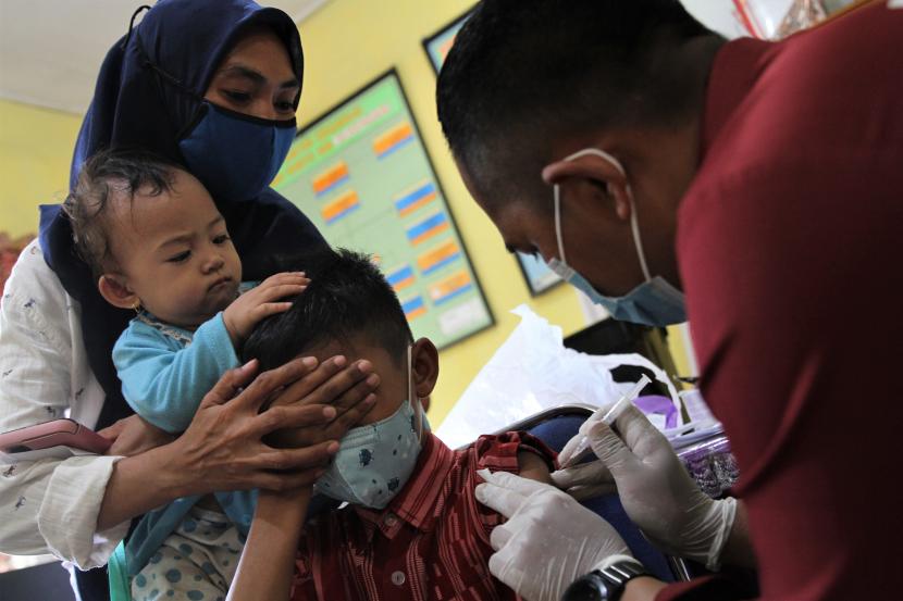Tim medis Polresta Kendari menyuntikkan vaksin COVID-19 kepada seorang siswa di SD Negeri 30 Kendari, Kendari, Sulawesi Tenggara, Rabu (26/1/2022). Pemerintah Kota Kendari telah mulai melakukan vaksinasi COVID-19 kepada murid SD dengan sasaran siswa di 147 sekolah agar program percepatan vaksinasi di wilayah setempat segera terealisasi.