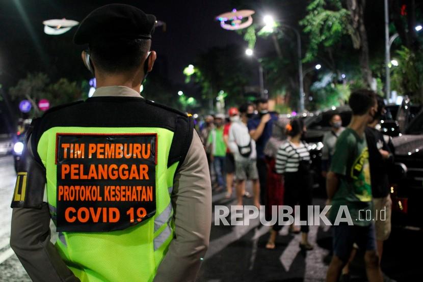 Tim Pemburu Pelanggar Protokol Kesehatan COVID-19 menjaga warga yang terjaring di Jalan Darmo, Surabaya, Jawa Timur, Rabu (16/9/2020) malam. Tim Pemburu Pelanggar Protokol Kesehatan COVID-19 yang bergerak di berbagai kawasan di Surabaya itu menjaring sejumlah orang yang tidak menggunakan masker dan selanjutnya disidang dengan sanksi denda. 