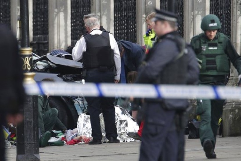 Tim penanganan darurat menangani seorang warga terkuka dekat Istana Westminster, London, Rabu (22/3). Serangan di luar gedung parlemen Inggris menewaskan lima orang.