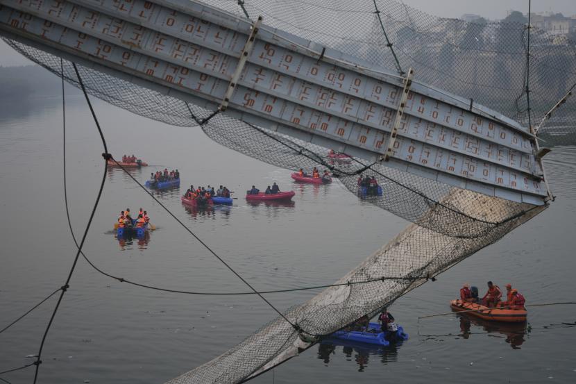  Tim penyelamat di kapal mencari di sungai Machchu di sebelah jembatan gantung kabel yang runtuh di kota Morbi di negara bagian barat Gujarat, India, Senin, 31 Oktober 2022. Jembatan kabel gantung berusia seabad runtuh ke sungai Minggu malam, mengirim ratusan terjun ke air, kata para pejabat.