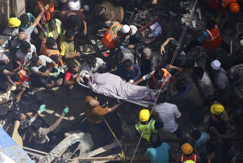 Tim penyelamat membawa mayat seorang korban di lokasi sebuah bangunan yang runtuh di Mumbai, India, Selasa, 16 Juli 2019.