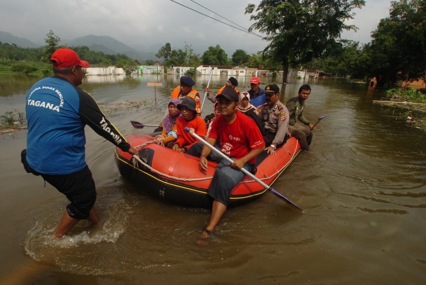 Tim SAR gabungan membantu warga menyebrangi jalan yang digenangi air Waduk Jatigede di Darmaraja, Sumedang, Jawa Barat, Senin (16/2). 