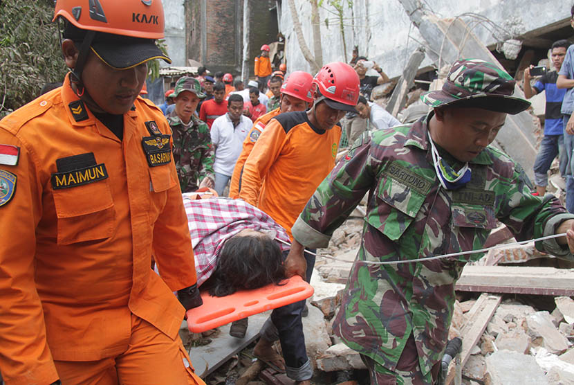 Tim SAR memandu korban selamat seusai dievakuasi dari reruntuhan bangunan akibat gempa di Desa Ulee Glee, Kecamatan Bandar Dua , Kabupaten Pidie Jaya, Aceh, Rabu (7/12). 