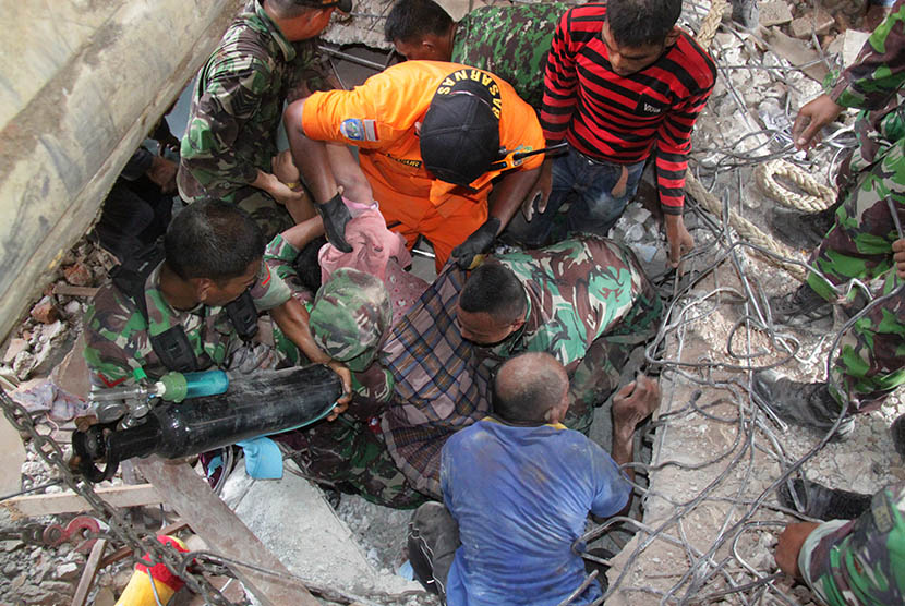 SAR teams evacuate victims trapped in the collapsed building of Trienggadeng Market after the earthquake hit Pidie Jaya, Aceh, Wednesday (12/7).