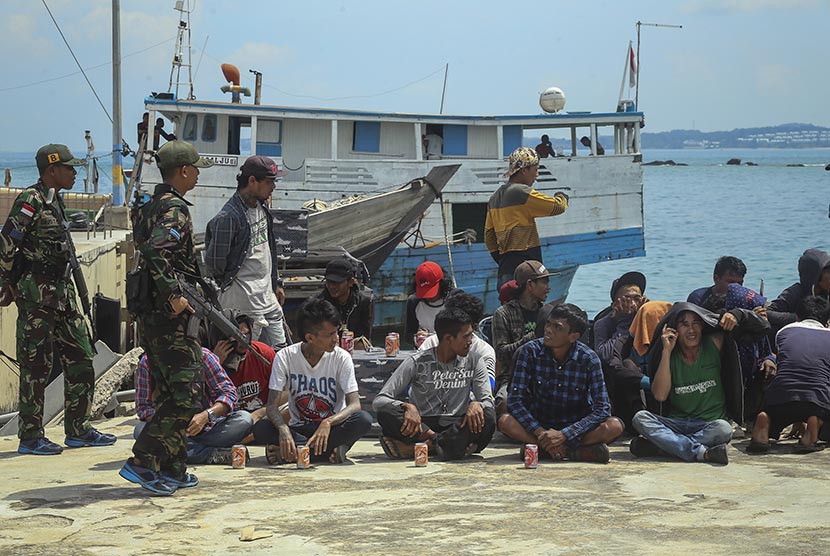 Tim Western Fleet Quick Response (WFQR) Lantamal IV Tanjungpinang menjaga tenaga kerja Indonesia (TKI) ilegal yang berhasil diamankan saat akan diberangkatkan menuju Malaysia di Dermaga Pangkalan Angkatan Laut Batam, Kepulauan Riau, Rabu (7/12). 